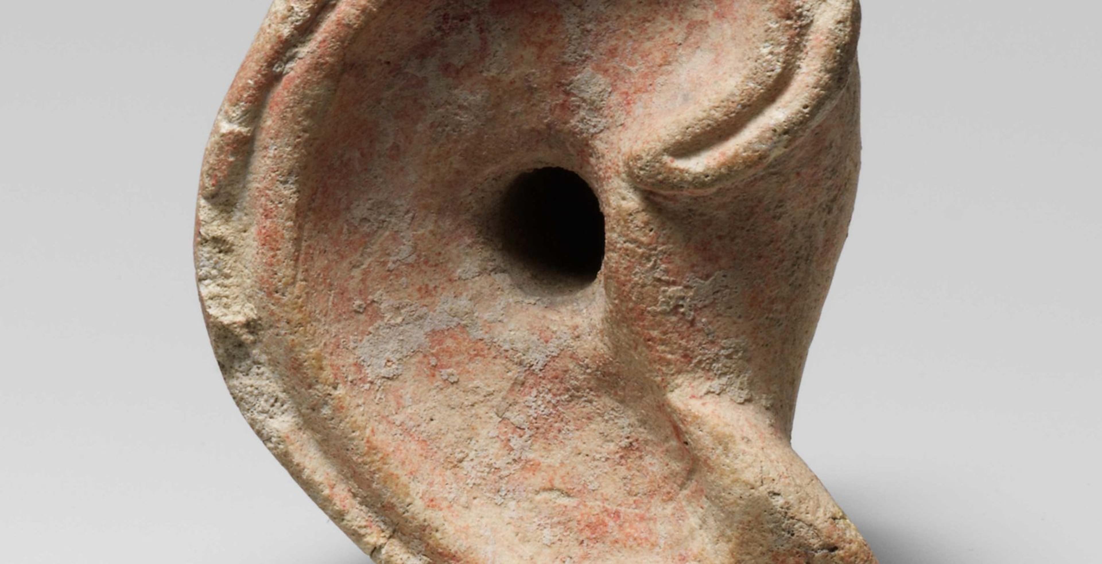 Sculpture of a right ear with the canal indicated by a circular hole, traces of red paint, and five syllabic signs carved into the lobe