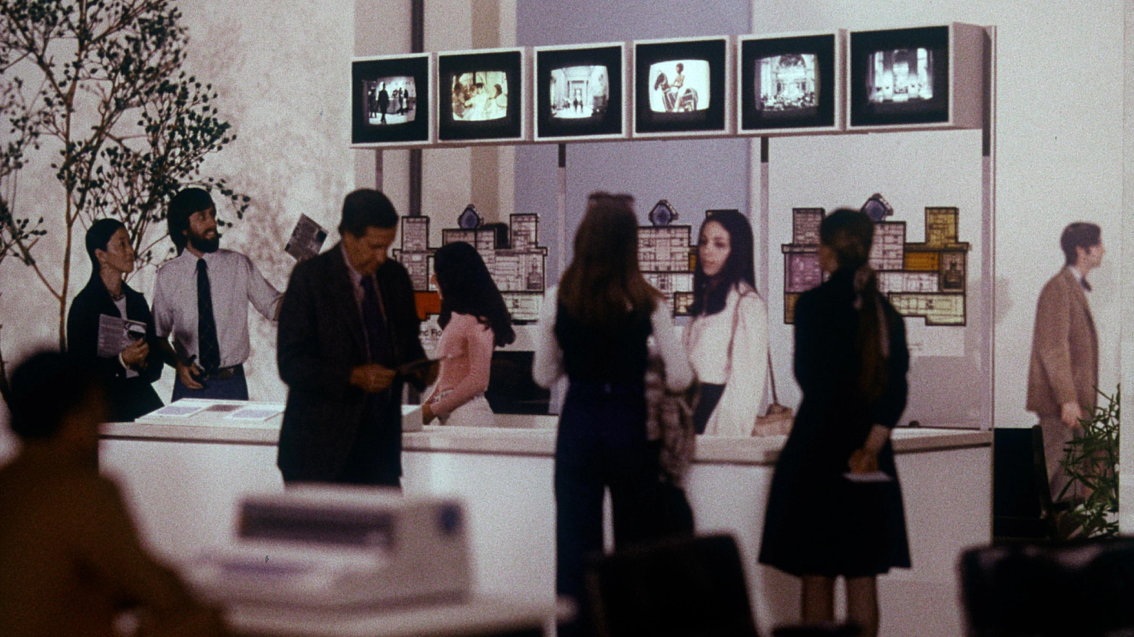 Archival image of model figures examining technology displays and floorplans at The Met.