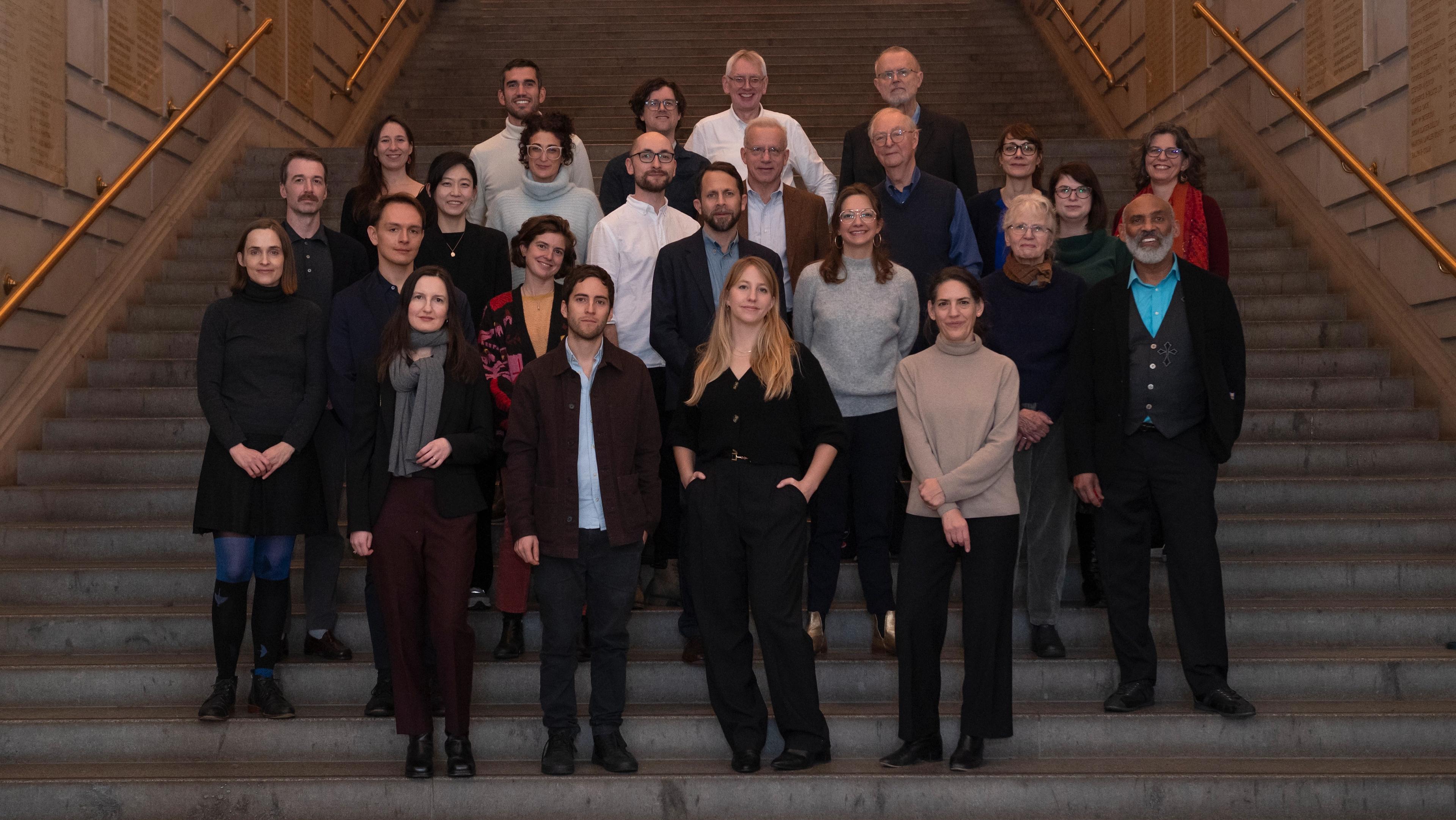 A collection of adults standing on the Great Hall steps inside The Met Museum.