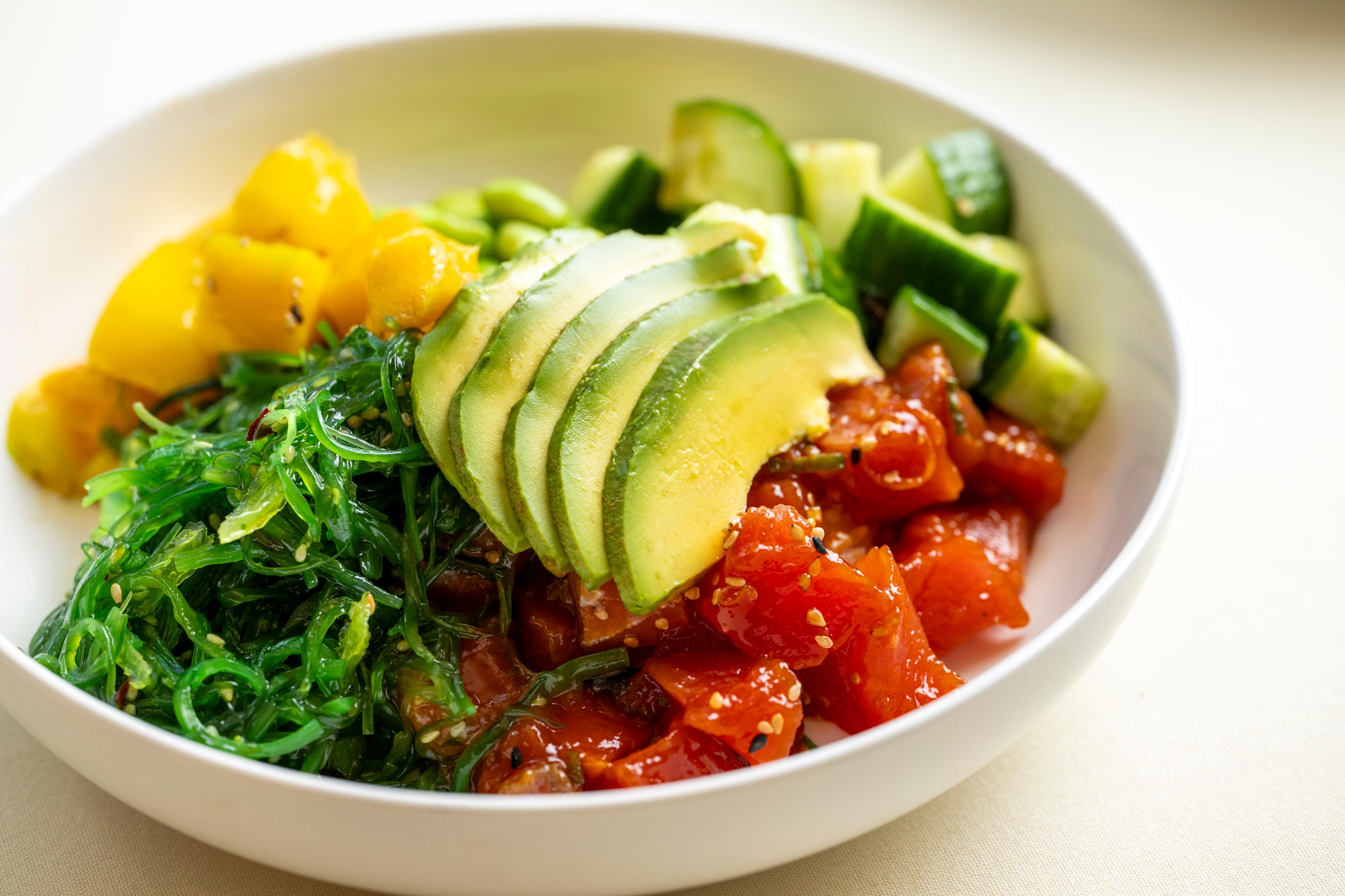 A poke bowl with avocado, tuna, cucumber and seaweed.