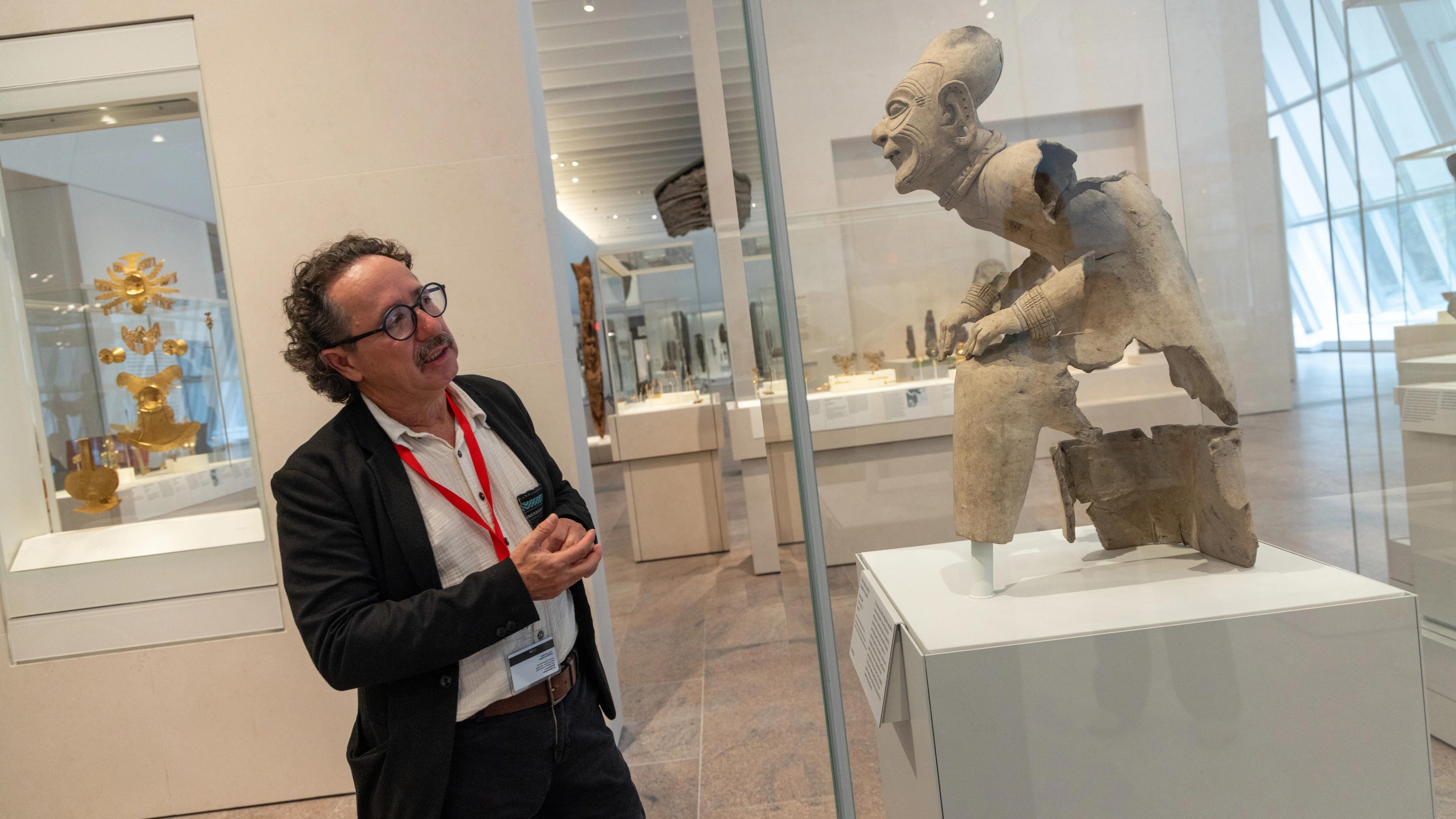 Florencio Delgado Espinoza gazes at the seated elder statue in the Arts of the Ancient Americas galleries.