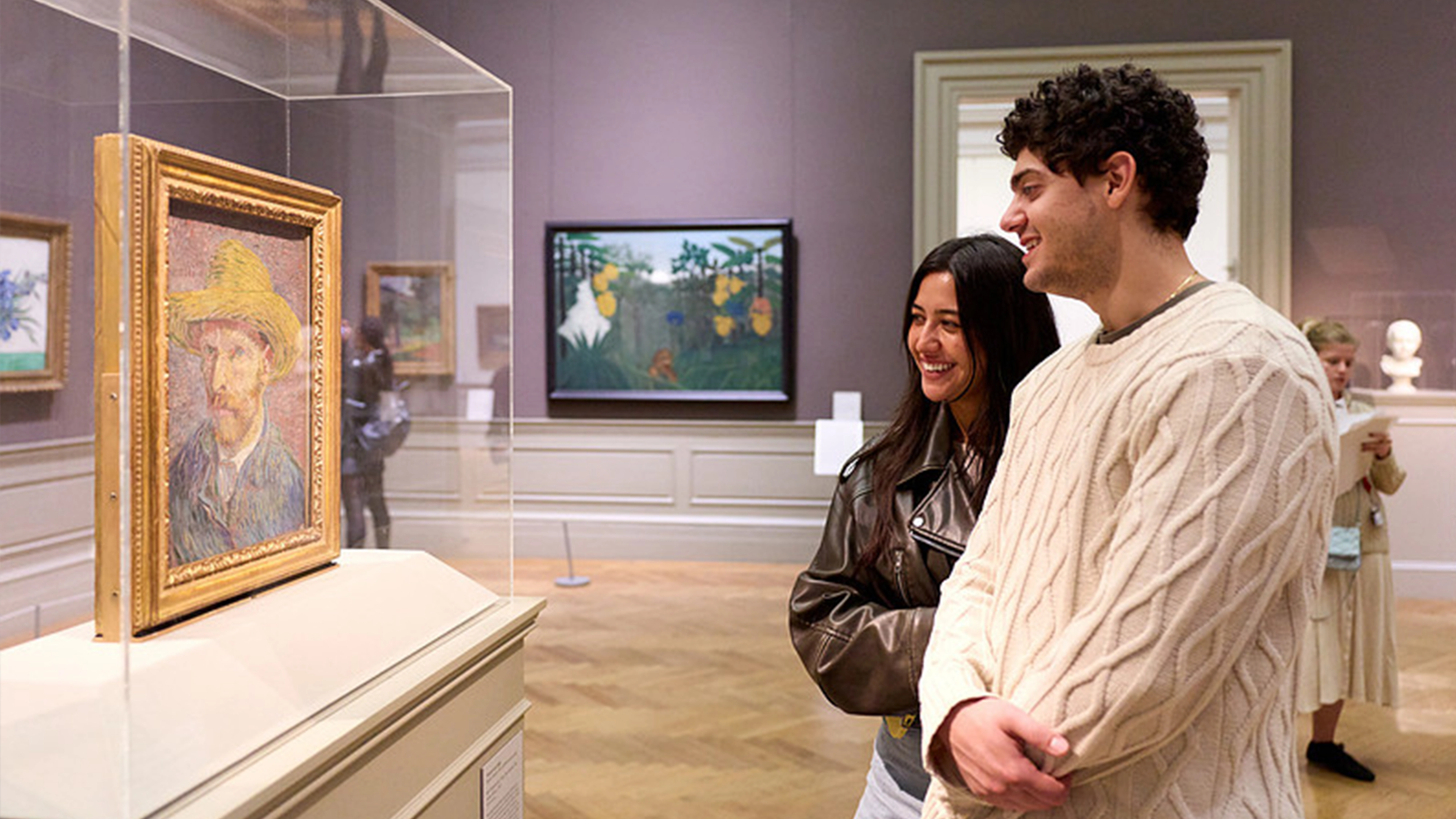 Couple standing in front of Vincent Van Gogh's Self-Portrait with a Straw Hat (obverse: The Potato Peeler)