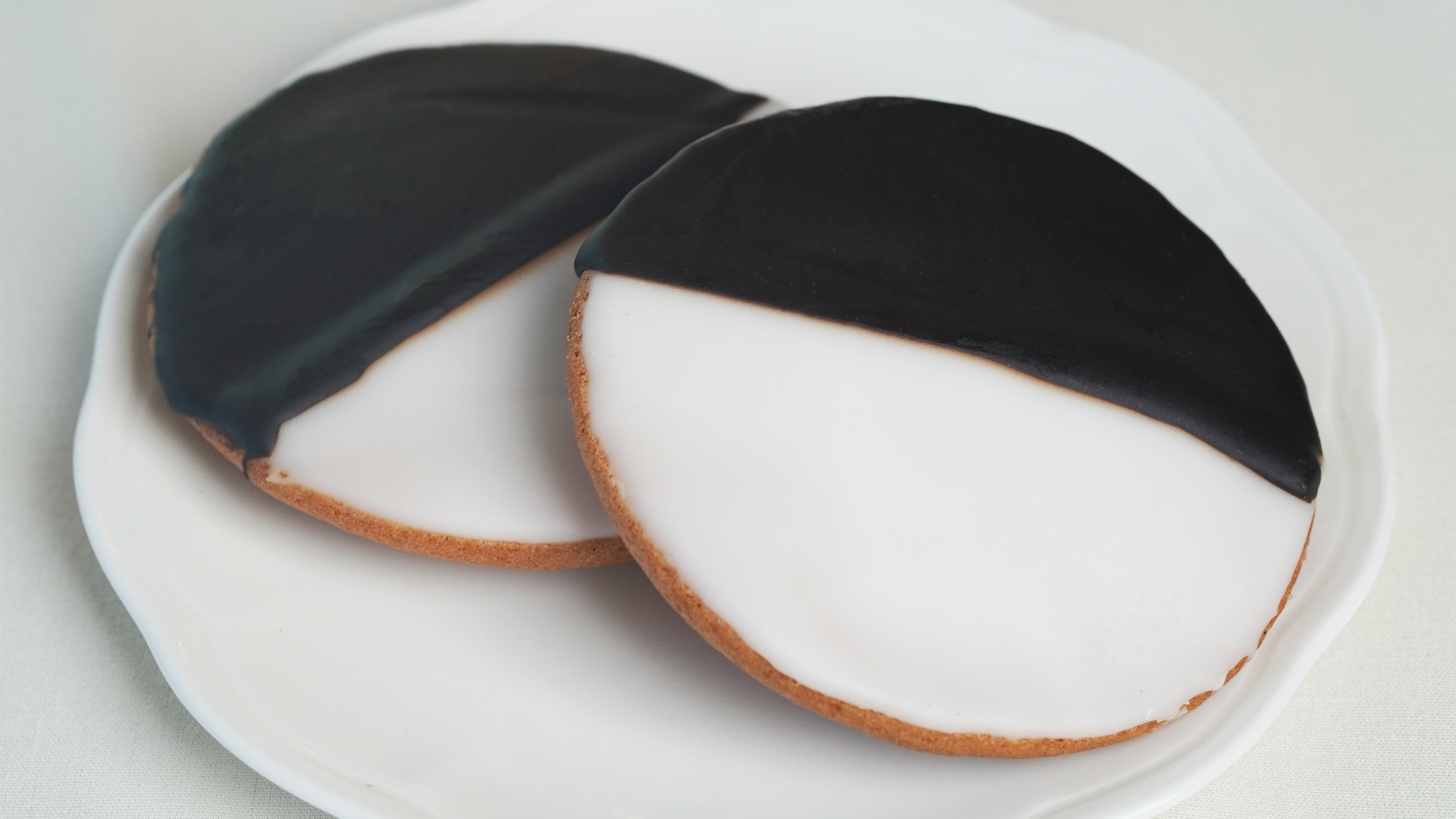 Two black and white cookies on a plate. 